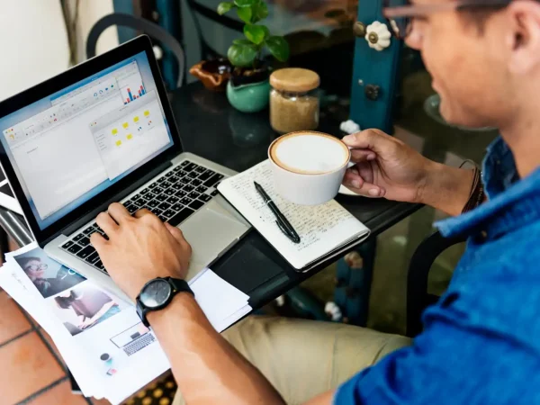 Pessoa trabalhando no computador com gráficos e anotações, ideal para quem busca dicas sobre como conseguir os primeiros clientes no digital.