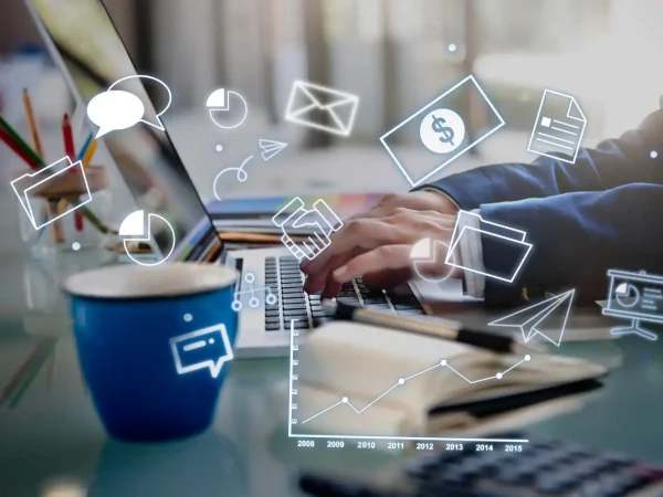 Pessoa trabalhando em um notebook com ícones de comunicação e negócios ao seu redor, representando estratégias de precificação de serviços como consultoria, marketing ou design.