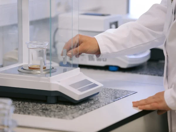 Imagem de um profissional ajustando uma balança de precisão em laboratório, destacando os erros de pesagem que podem gerar prejuízo financeiro para empresas.