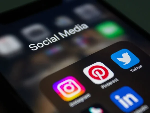 Imagem de um smartphone com ícones de mídia social, incluindo Instagram, Pinterest, Twitter e LinkedIn, relacionado a estratégias de crescimento orgânico e M&A para empresas industriais.