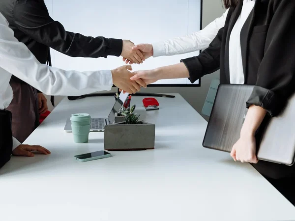 Negociação de grandes contas em mercado B2B com profissionais apertando as mãos, simbolizando fechamento de negócios e estratégias de precificação.