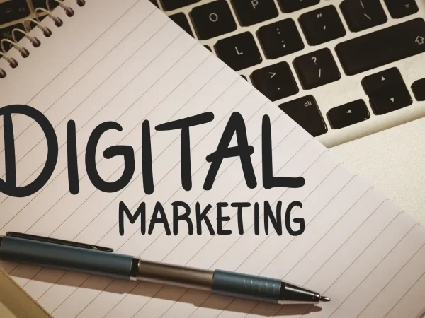 Imagem com bloco de anotações e caneta sobre teclado de computador, com o texto “DIGITAL MARKETING” em destaque. Tema relacionado ao Fim dos Cookies de Terceiros e marketing digital online.