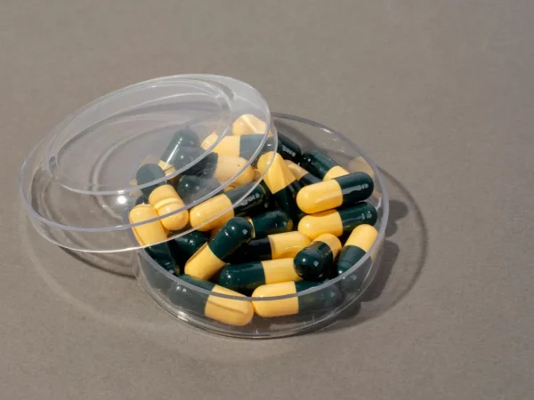 Pote transparente com cápsulas em duas cores, amarelas e verdes, demonstrando Encapsulados Personalizados: vantagens, qualidade e quando optar por essa solução